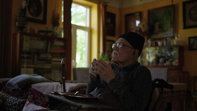 Old man in a wheelchair watching tv in the livingroom at home
