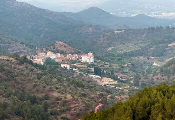 Obraz premium Town on Mountains landscape on sunset. Mountain view from Mola De Segart mountain in Sierra Calderona national park in Valencia, Spain.House in mountains. Landscape of a mountain valley.