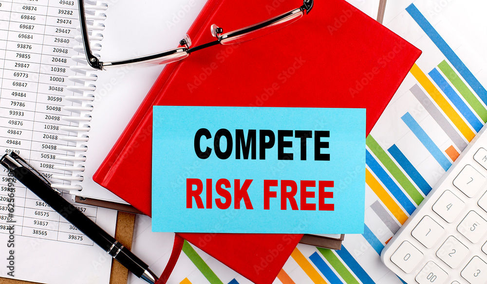 Poster compete risk free text on a sticky on red notebook on chart background