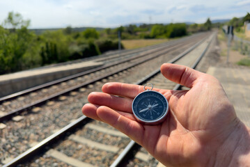 Compass in hand at railway station. Tourist compass for orientation on terrain. Magnetic...