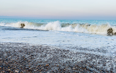 Pebble stone beach on sunrise. Sea beach shore with waves in ocean. Waves in sea on sunset. Empty coastline pebble beach. Sea beach landscape. Shore landscape on Spain resort. Ocean shoreline scenic.