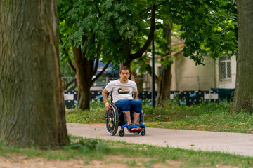 Inclusiveness Portrait of a young man with a disability in a wheelchair in a city park against a background of trees 