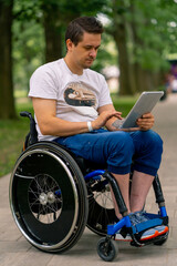 Inclusiveness A man with disabilities in a wheelchair stares intently at the tablet he is holding...