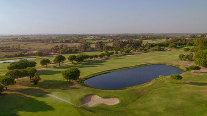 Fototapeta na wymiar Fairway, sand bunker and lake on golf course at sunset. Spain. Aerial view.