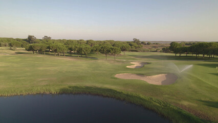 Fototapeta na wymiar Golf course. Aerial view of greens, fairway, lake and sand bunkers on golf course at sunset. Spain.