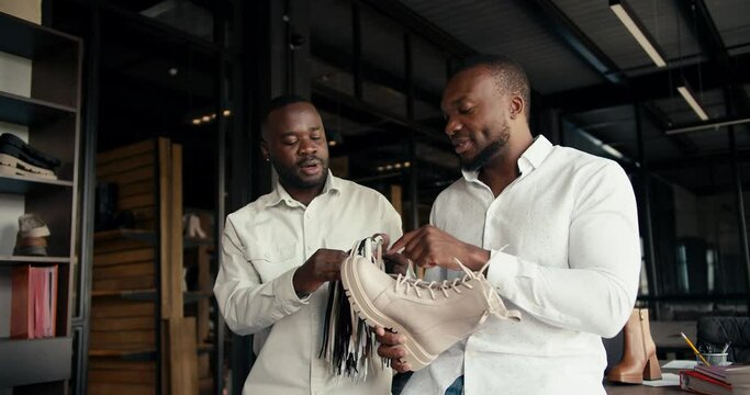Two designer businessmen with Black skin color in white shirts are discussing new laces for a shoe party