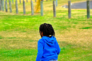  beautiful young black African boy with dreadlocks playing in a park .