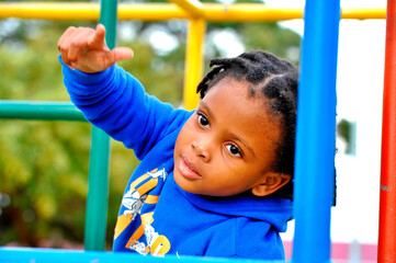 Fototapeta premium beautiful young black African boy with dreadlocks playing in a park .