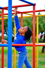 Fototapeta premium beautiful young black African boy with dreadlocks playing in a park .