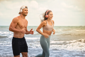 Sport man and woman running on beach at sunset. Summer concept