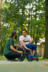 Fototapeta premium Inclusiveness A man with disabilities communicates with an elderly man with long hair and gray beard in a city park with trees in the background