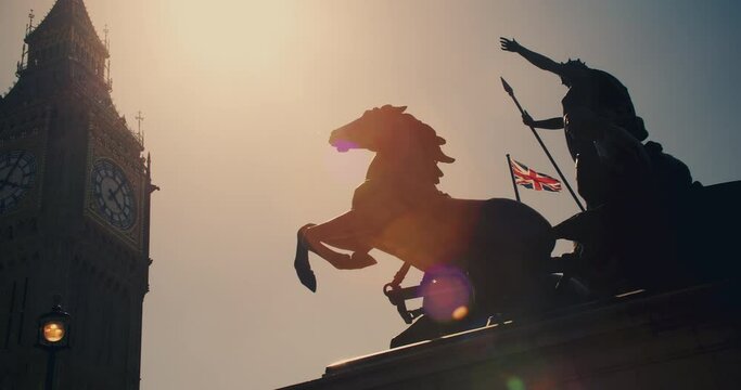 Panning shot to Big Ben, Houses of Parliament from Boadicea or Boudica statue on Westminster Bridge at sunset, London, England