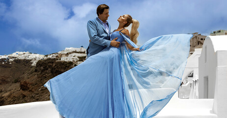 Summer love. Beautiful happy young couple lovers in elegant blue wedding clothes is posing in Fira...