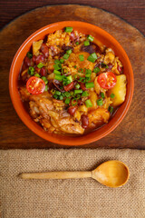 ready-made cholent dish, sprinkled with green onions, in a clay plate on the table