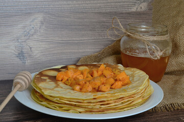 a plate of pancakes with apricots on burlap and honey