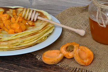 a plate with pancakes with apricots on the table