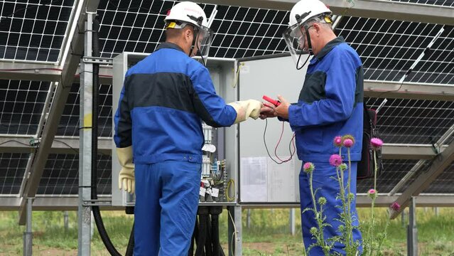 Two Service Engineers or electrician working on checking transformer site and solving problem for green energy solar power plant operation. Technician maintenance solar cells on Solar Energy Plant