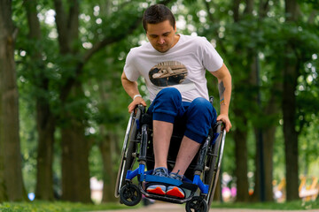 Inclusiveness A man with a disability does wheelchair stunts in a city park against a backdrop of...