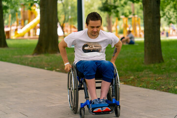 Inclusiveness A man with disabilities rides a wheelchair along the path of a city park against the background of trees 