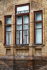Window with a wooden frame and an old red brick wall with damaged texture