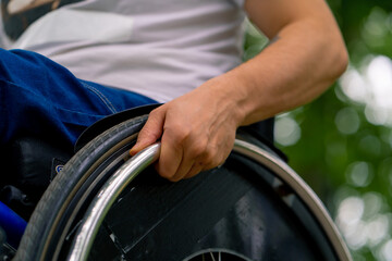 Inclusiveness Close-up of the hand of a man with disabilities who rides a wheelchair in a city park 