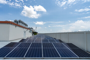 Solar panels placed on top of roof of industrial structure against blue cloudless sky background.