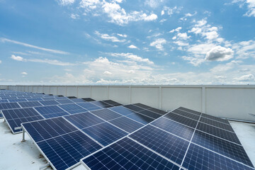 Solar panels placed on top of roof of industrial structure against blue cloudless sky background.
