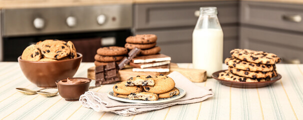 Many tasty cookies with chocolate on table in kitchen