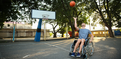 Young man in wheelchair playing basketball outdoors