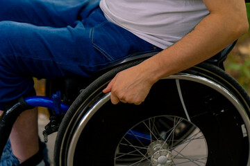 Inclusiveness Close-up of the hand of a man with disabilities who rides a wheelchair in a city park 