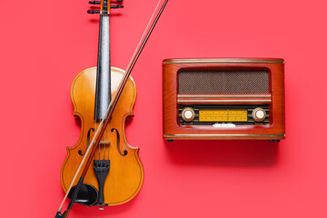 Violin and retro radio receiver on color background