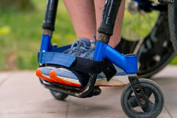 Inclusiveness Close-up of the legs of a man with disabilities who rides a wheelchair in a city park 