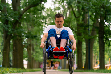 Inclusiveness A man with a disability does wheelchair stunts in a city park against a backdrop of trees