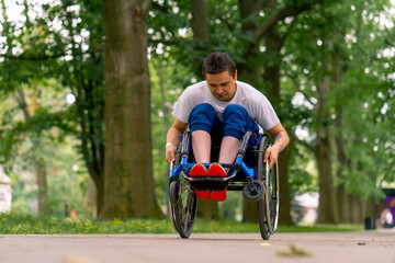 Inclusiveness A man with a disability does wheelchair stunts in a city park against a backdrop of...