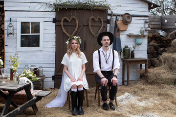 Obraz premium country bride in a white short dress and groom in a white shirt in the village wedding, boho style.