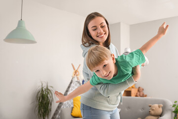Nanny with little boy playing at home