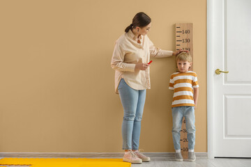 Little boy with nanny measuring height at home