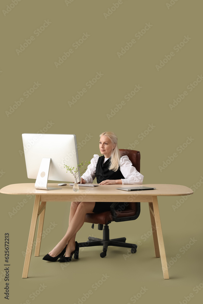 Poster mature female programmer working with computer at table on green background