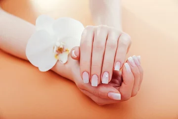  Ombre french manicure with orchid on orange background. Close up of nail art with white orchid flower. Salon © maryviolet