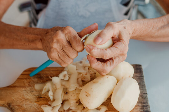Close up hands brazilian elderly woman peeling potatoes