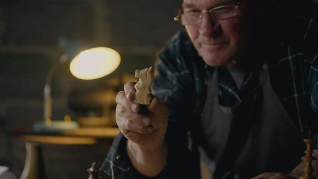 Shavings, Man Focusedly Examines the result of cutting chess pieces In the workshop Tracking shot Junior specialist Spends working time studying new ideas In the workshop of a craftsman, wooden bar