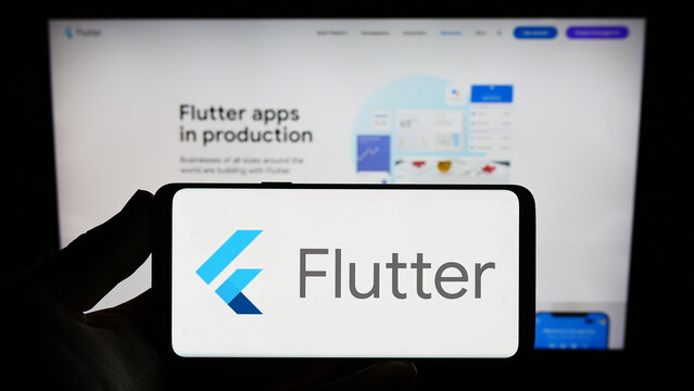 Stuttgart, Germany - 07-09-2023: Person holding smartphone with logo of UI software development kit Flutter (Google) on screen in front of website. Focus on phone display.