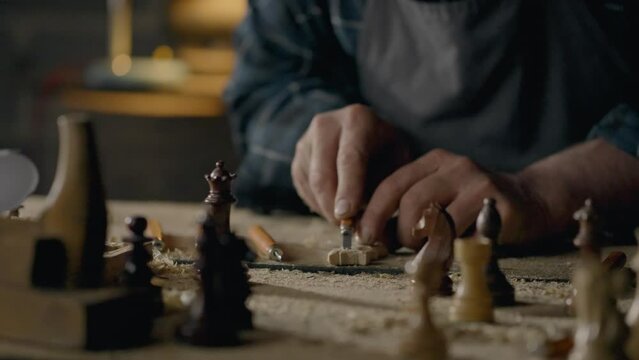 Sawdust, Man furniture maker Slowly Carving chess pieces In the workshop In slow motion Skilled craftsman Concentrated on the task of making In the chess workshop, blank