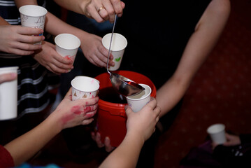 Halloween kids party. Children pour red drink into glasses.