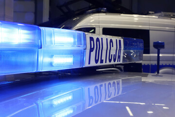 Radiowóz polska policja z Sygnalizator błyskowy niebieski na dachu radiowozu. Alarmowo wieczorem - obrazy, fototapety, plakaty