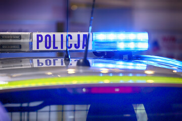 Radiowóz polska policja z Sygnalizator błyskowy niebieski na dachu radiowozu. Alarmowo wieczorem © FotoDax