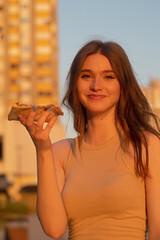 portrait of a woman eating a slice of pizza and smiles
