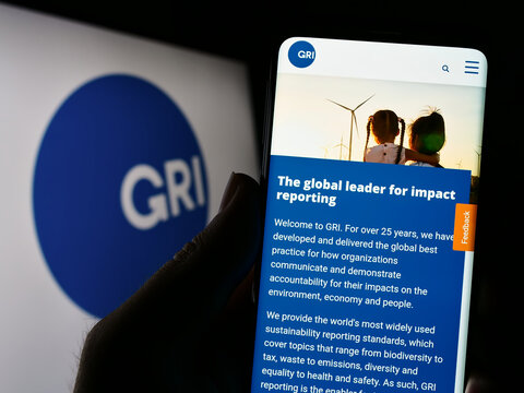 Stuttgart, Germany - 07-11-2023: Person holding cellphone with webpage of the Global Reporting Initiative (GRI) on screen in front of logo. Focus on center of phone display.