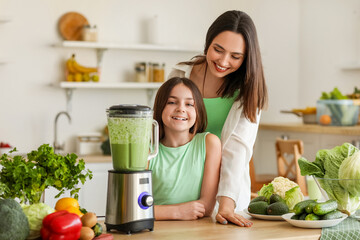 Little girl and her mother making vegetable smoothie with blender in kitchen - obrazy, fototapety, plakaty