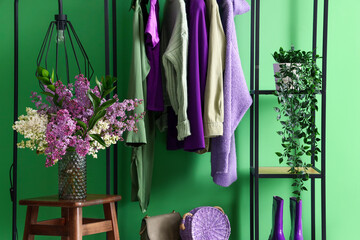 Stylish clothes hanging near green wall in room